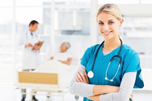 Young smiling doctor standing in hospital with colleagues talking to patient in background